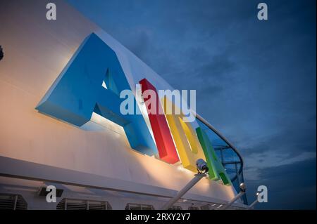 Farbenfrohes AIDA-Logo, das am AIDA Bella-Kreuzfahrtschiff in der Nacht angebracht ist, mit bewölktem Himmel und Blick auf den niedrigen Winkel Stockfoto