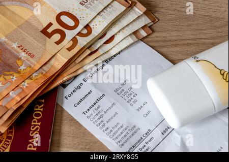 Ein Reisegeld-, Urlaubs- und Geldwechselkonzept mit Euro-Banknoten, einem Reisepass, Sonnencreme auf einem Geldwechselbeleg. Stockfoto