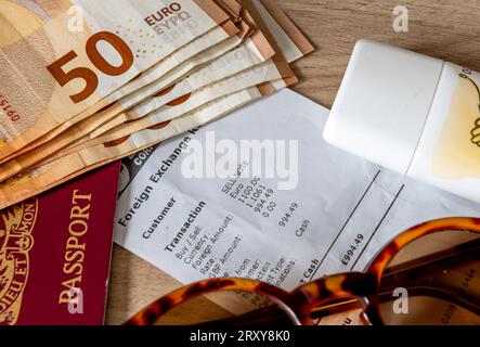 Ein Reisegeld-, Urlaubs- und Geldwechselkonzept mit Euro-Banknoten, einem Reisepass, Sonnencreme und Sonnenbrille auf einem Wechselbeleg. Stockfoto