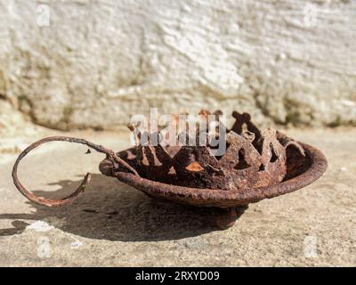 Nahaufnahme eines alten, rostigen und verwitterten Kerzenleuchters aus Zinn, der im Dreck vor der rustikalen Mauer eines Bauernhofs in der Nähe der Stadt Arcabuco gefunden wurde. Stockfoto