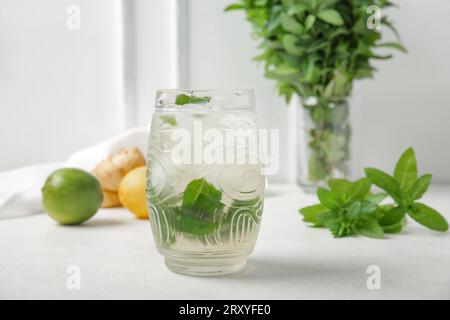 Glas frischer eiskalter Minztee mit Ingwerwurzel und Zitrusfrüchten auf weißem Hintergrund Stockfoto