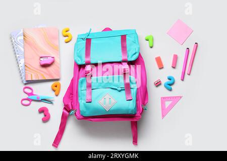 Stylischer Schulrucksack mit verschiedenen Schreibwaren auf grauem Hintergrund Stockfoto