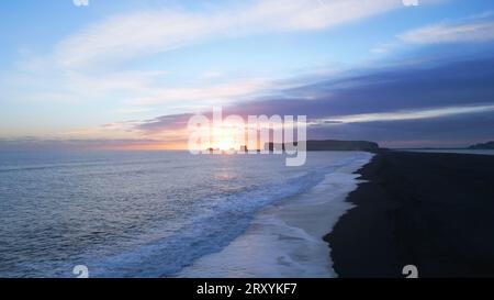 Reynisfjara schwarzer Sandstrand in island, wunderschöne Landschaft mit Sonnenuntergang und Wellen, die an der Küste krachen. Drohnenaufnahme der isländischen Küste und der nordischen Landschaften, reynisfjall Mountain. Zeitlupe. Stockfoto