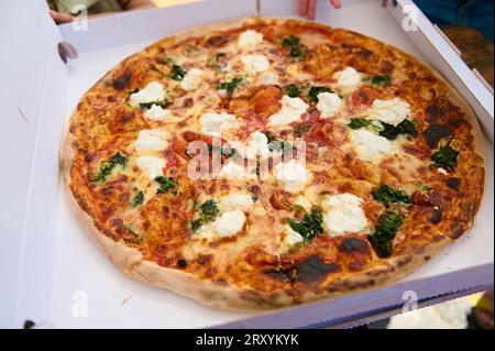 Neapolitanische hausgemachte Pizza Margarita aus dem Backofen in einer Einwegkarton. Italienische Pizza Napoleon mit frischem Mozzarella und Basilikumblättern. Stockfoto