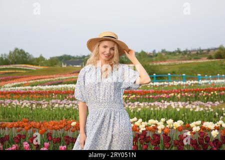 Glückliche Frau im schönen Tulpenfeld draußen Stockfoto