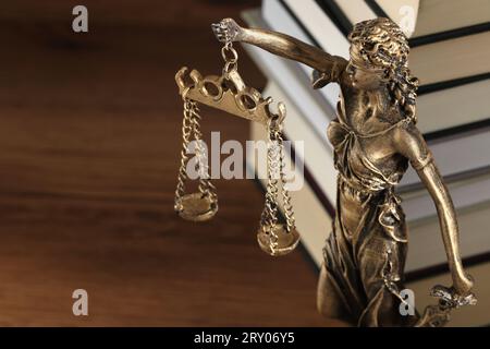 Symbol der gerechten Behandlung nach dem Gesetz. Figur der Lady Justice und Bücher auf Holztisch, Nahaufnahme mit Platz für Text Stockfoto