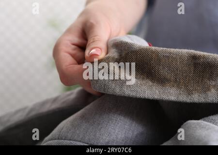 Frau zeigt Flecken vom Kaffee auf der Jacke vor verschwommenem Hintergrund, Nahaufnahme Stockfoto