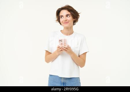 Porträt einer brünetten Frau mit Smartphone, stehend mit Handy, SMS, Bestellung aufgeben, soziale Medien am Telefon durchstöbern, stehen Stockfoto