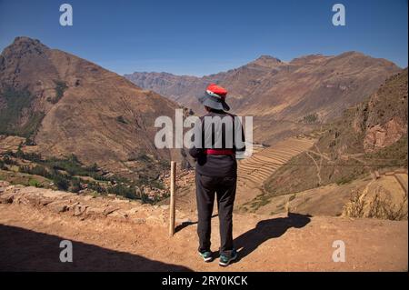 Rückansicht der Frau, die auf der archäologischen Stätte Pisac steht, mit wunderschönem Blick auf landwirtschaftliche Terrassen Stockfoto