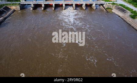 Die Luftaufnahme des Wassers, das aus dem Abflusskanal des Betondamms freigesetzt wird, ist eine Möglichkeit, in der Regenzeit überlaufendes Wasser zu bekommen. Draufsicht auf die trübe Stirn Stockfoto