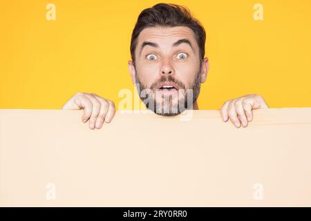 Informationskonzept. Überraschter Mann mit leerem Schild. Demonstrieren des Kopierraums für Text oder Design. Staunender, aufgeregter Mann mit leerer Werbung Stockfoto