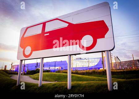 28. September 2023, Niedersachsen, Wolfsburg: Ein großes Piktogramm vor dem Hauptwerk von Volkswagen zeigt ein Auto am frühen Morgen. Volkswagen sagt, dass es die IT-Fehlfunktion behoben hat, die die Produktion in mehreren Werken seit Mittwoch gelähmt hat. Die Produktion steigt nun wieder an. Foto: Moritz Frankenberg/dpa Stockfoto