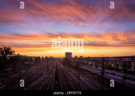 28. September 2023, Niedersachsen, Wolfsburg: Der Himmel über den Gleisen des Hauptbahnhofs scheint bei Sonnenaufgang. Foto: Moritz Frankenberg/dpa Stockfoto