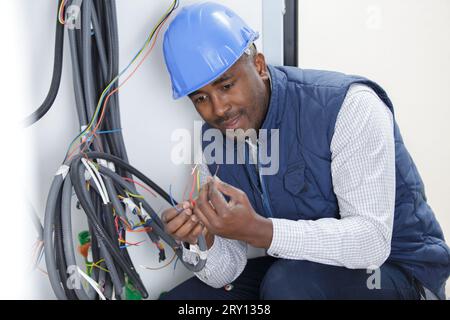 Elektriker, der den Spannungspegel in den Steckdosenkabeln überprüft Stockfoto
