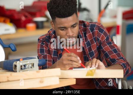 Junger Mann im Rollstuhl versucht sich selbst, sein Bücherregal zu falten Stockfoto