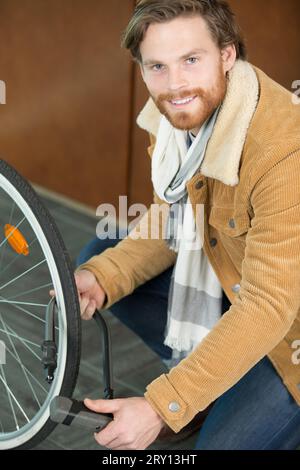 Junger Mann, der mit einer kleinen Pumpe einen Radreifen aufpumpt Stockfoto