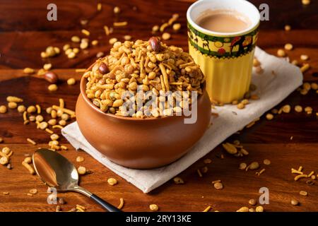 Traditionelles indisches frittiertes salziges und würziges Gericht - Chivda oder Mischung oder farsan oder Namkeen aus Grammehl und gemischt mit Nüssen. Serviert mit einer heißen Tasse Stockfoto