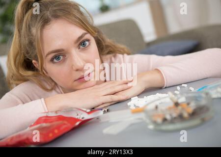 Porträt einer unglücklichen jungen Dame neben einem Aschenbecher Stockfoto