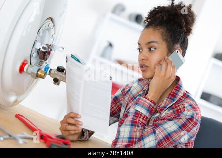 weibliche Klempner Prüfung Rohre der Zentralheizungskessel Stockfoto