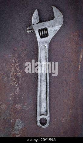 Ein alter verstellbarer Schraubenschlüssel liegt auf einem Stück rostigem Metall Stockfoto