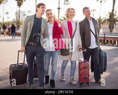 Touristen mit Koffern und Kamera spazieren auf dem Bürgersteig im Hafen der europäischen Stadt Stockfoto