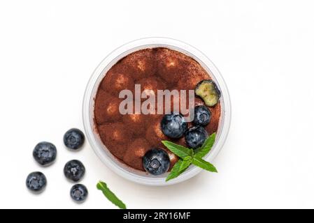 Traditionelles italienisches süßes Dessert aus Tiramisu-Kuchen im Glas auf weißem Hintergrund. Mit einer erfrischenden, gesunden Zugabe von großen, saftigen Heidelbeeren. Flach Stockfoto