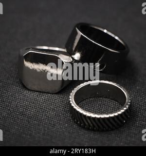 Nahaufnahme von metallischen Platin-Luxusringen mit minimalistischem Design aus einem Modeschmuckgeschäft, isoliert in einem schwarzen Hintergrund Stockfoto
