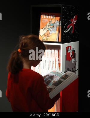 (230928) -- BRÜSSEL, 28. September 2023 (Xinhua) -- Ein Mädchen liest ein Buch auf einer Ausstellung, die auf der Comic-Serie "die Abenteuer von Tintin" in Brüssel, Belgien, 27. September 2023 basiert. Die digitale Ausstellung erstreckt sich über eine 1.600 Quadratmeter große Projektionsfläche und ermöglichte es den Besuchern, in die Welt von Tintin einzutauchen. (Xinhua/Zhao Dingzhe) Stockfoto