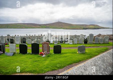 Friedhof auf Shetland Island auf einem Hügel mit Meer im Hintergrund an bewölkten Tagen Stockfoto