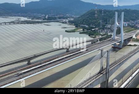 (230928) -- FUZHOU, 28. September 2023 (Xinhua) -- dieses Luftbild vom 28. September 2023 zeigt einen Fuxing-Hochgeschwindigkeitszug, der auf der Wulong-Flussbrücke entlang der Fuzhou-Xiamen-Zhangzhou-Hochgeschwindigkeitsbahn in der südöstlichen chinesischen Provinz Fujian fährt. Chinas schnellste Hochgeschwindigkeitsstrecke für den Seeverkehr nahm am Donnerstag den Betrieb auf, wobei die Züge mit einer Höchstgeschwindigkeit von 350 km/h entlang der Westküste der Straße von Taiwan verkehrten. Ein Fuxing-Hochgeschwindigkeitszug G9801 fuhr um 9:15 Uhr von Fuzhou, der Hauptstadt der südöstlichen chinesischen Provinz Fujian, ab und feierte die Eröffnung der 277 km langen Hochgeschwindigkeitsbahn Fuzhou-Xiamen-Zhangzhou. Stockfoto