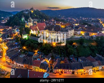 Die mittelalterliche Festung und die Stadt Sighisoara in der Abenddämmerung aus der Luft. Foto aufgenommen am 14. August 2023 in Sighisoara, Transsilvanien, Rumänien. Stockfoto