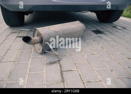 Das rostige Auspuffrohr, der Schalldämpfer des Autos ist abgefallen und liegt auf der Straße Stockfoto