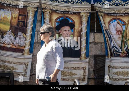 Jerusalem, Israel. 28. September 2023. Eine Frau geht an einer vielseitigen Sammlung von Bildern vorbei, die zur Dekoration der Sukkah verkauft werden, einem Tabernakel, das die Schutzräume symbolisiert, die von den alten Hebräern in der Wildnis genutzt wurden, nachdem sie in Ägypten aus der Sklaverei befreit wurden. Die Vorbereitungen für Sukkot, das jüdische fest der Tabernakel, sind im Gange. Quelle: Nir Alon/Alamy Live News. Stockfoto