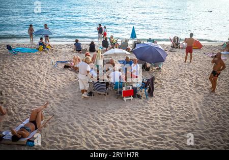 Eine Gruppe älterer Freunde spielt Karten am öffentlichen Strand von Zamenhof am späten Nachmittag in Cannes in Südfrankreich. Stockfoto