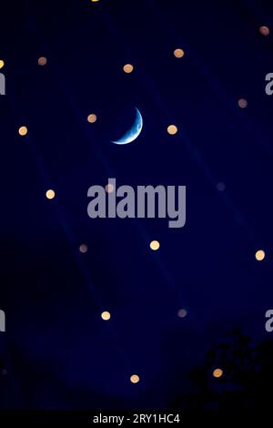 mondsichel am klaren Himmel zwischen dem Bokeh des Lichts. Stockfoto