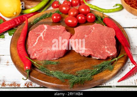 Rindfleisch runde Scheibe auf Holzhintergrund. Rohes Rindfleisch rund mit Kräutern und Gewürzen Stockfoto