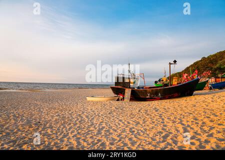 Sonnenuntergang am Strand an der polnischen Ostsee. Fischerboot am Abend in der Nähe von Międzyzdroje, Polen. Stockfoto