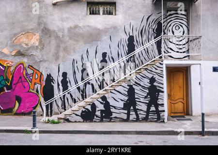 Ein großes Wandgemälde auf einem Gebäude, das eine lustige Gruppe von Menschen zeigt, die Treppen zu einem Club gehen. Es gibt ein Pferd, eine Katze, einen Punk und andere Leute. In Tiflis, Ge Stockfoto