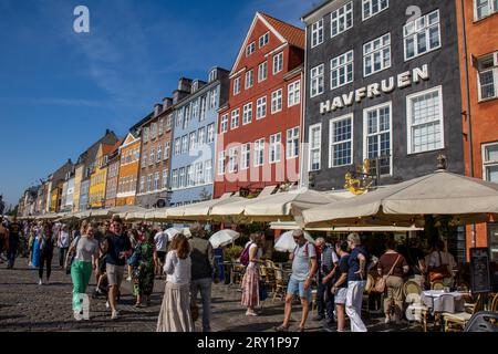 Gente llenando el paseo Marítimo y las terrazas junto al Canal en Nyhavn, uno de los lugares con más encanto de Copenhague con sus casas coloridas. Stockfoto