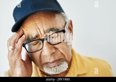 Kopfschmerzen, Schmerzen und Gesicht des älteren Mannes mit Müdigkeit, Burnout oder Problem mit der Gesundheit auf weißem Hintergrund. Stress, Migräne und frustrierter älterer Mensch Stockfoto