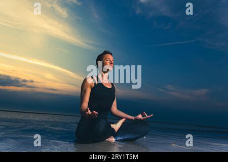Sportliche Frau, Die Yoga Am Meer Macht Stockfoto