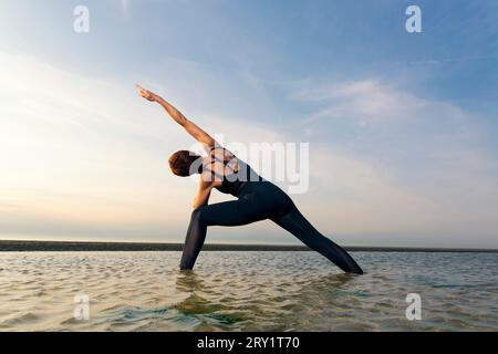Sportliche Frau, Die Yoga Am Meer Macht Stockfoto
