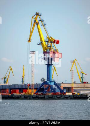 Seehafen mit Kränen und Frachtcontainern mit Gütern. Globaler Versand und Logistik. Ein großer, heller neuer Kran vorne. Hochwertige Fotos Stockfoto