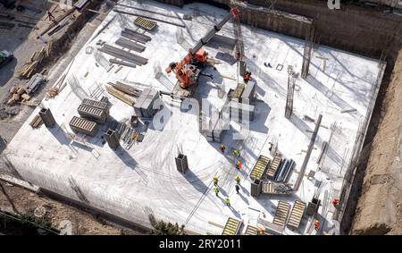 Draufsicht von oben nach unten auf einer Baustelle mit einem Team von Arbeitern. Schwere Krane und Bauarbeiter arbeiten. Hochwertige Fotos Stockfoto