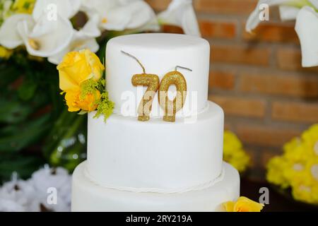 Detail der Zahl siebzig oben auf dem Geburtstagskuchen, 70 Geburtstag, weißer Kuchen, 70 Jahre alte Geburtstagskuchen Kerze Stockfoto