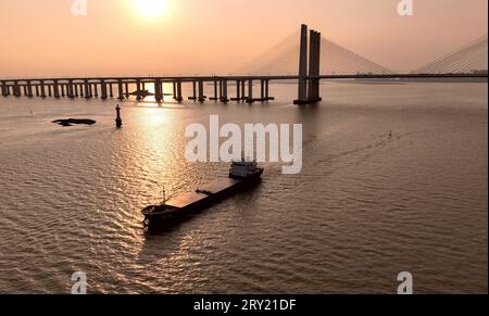 (230928) -- FUZHOU, 28. September 2023 (Xinhua) -- dieses Luftbild vom 18. September 2023 zeigt ein Frachtschiff, das in Richtung der Quanzhou Bay-Überseebrücke entlang der Fuzhou-Xiamen-Zhangzhou-Hochgeschwindigkeitsbahn in der südöstlichen chinesischen Provinz Fujian segelt. Chinas schnellste Hochgeschwindigkeitsstrecke für den Seeverkehr nahm am Donnerstag den Betrieb auf, wobei die Züge mit einer Höchstgeschwindigkeit von 350 km/h entlang der Westküste der Straße von Taiwan verkehrten. Ein Fuxing-Hochgeschwindigkeitszug G9801 fuhr um 9:15 Uhr von Fuzhou, der Hauptstadt der südöstlichen chinesischen Provinz Fujian, ab und feierte die Eröffnung des 277 km langen Fuzhou-Xiamen-Zhangzhou High-spe Stockfoto