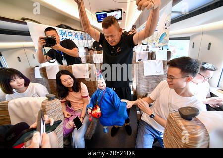 (230928) -- FUZHOU, 28. September 2023 (Xinhua) -- Eine Darstellerin spielt eine Marionettenshow auf dem Fuxing-Hochgeschwindigkeitszug G9801, der auf der Fuzhou-Xiamen-Zhangzhou-Hochgeschwindigkeitsbahn in der südöstlichen chinesischen Provinz Fujian verkehrt, 28. September 2023. Chinas schnellste Hochgeschwindigkeitsstrecke für den Seeverkehr nahm am Donnerstag den Betrieb auf, wobei die Züge mit einer Höchstgeschwindigkeit von 350 km/h entlang der Westküste der Straße von Taiwan verkehrten. Ein Fuxing-Hochgeschwindigkeitszug G9801 fuhr um 9:15 Uhr von Fuzhou, der Hauptstadt der südöstlichen chinesischen Provinz Fujian, ab und feierte die Eröffnung der 277 km langen Hochgeschwindigkeitsbahn Fuzhou-Xiamen-Zhangzhou. Das bin ich Stockfoto