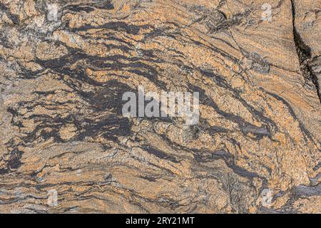 Hintergrundmuster aus braunem Granitstein. Unstrukturierte Linien der Fläche. Dunkle Farbe bricht mit leichten strukturellen Brüchen. Etwas graue Farbe Stockfoto