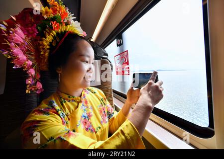 FUZHOU, 28. September 2023 (Xinhua) -- Ein Passagier, der an Bord des Fuxing-Hochgeschwindigkeitszuges G9801 mit der Fuzhou-Xiamen-Zhangzhou-Hochgeschwindigkeitsbahn reist, macht Fotos von der Landschaft vor dem Zugfenster in der südöstlichen chinesischen Provinz Fujian, 28. September 2023. Chinas schnellste Hochgeschwindigkeitsstrecke für den Seeverkehr nahm am Donnerstag den Betrieb auf, wobei die Züge mit einer Höchstgeschwindigkeit von 350 km/h entlang der Westküste der Straße von Taiwan verkehrten. Ein Fuxing-Hochgeschwindigkeitszug G9801 fuhr um 9:15 Uhr von Fuzhou, der Hauptstadt der südöstlichen chinesischen Provinz Fujian, ab und feierte die Eröffnung des 277 km langen Fuzhou-Xiamen-Zha Stockfoto