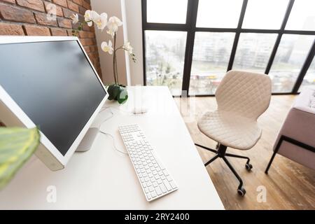Konzept des Arbeitsbereichs „Ausformung“. Weißer Bildschirm, moderner Desktop-Computer und Bücher, minimaler Aufwand auf dem Schreibtisch. Stockfoto